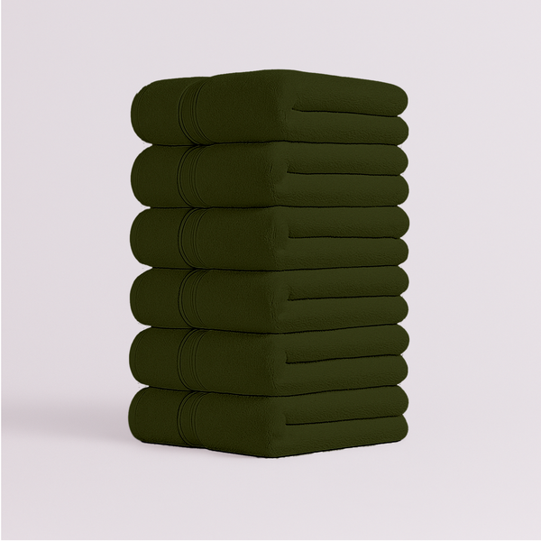 Stack of dark green bath towels folded neatly with soft plush texture
