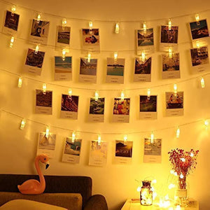 String lights with photo clips arranged on a wall, emitting warm white light, with a decorative flamingo and other room decor visible.