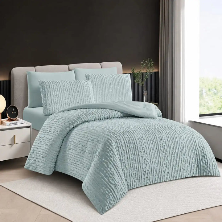 A light blue textured quilted bedding set with matching pillow shams on a bed in a modern bedroom setting.