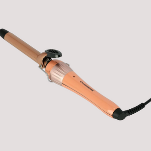 Rose gold hair curling iron with clamp and cylindrical barrel on a neutral background