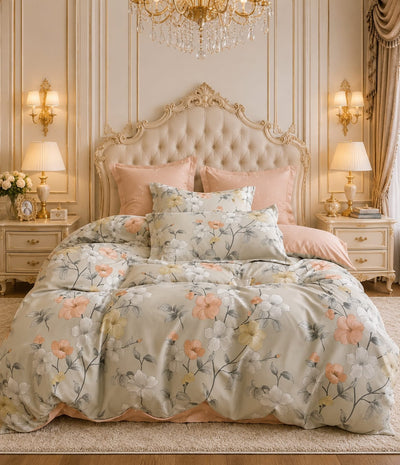 A beautifully styled bedroom featuring a floral duvet cover and matching pillow shams in soft peach, cream, and sage green tones, paired with solid blush pink pillows, set against an ornate beige tufted headboard and matching nightstands.