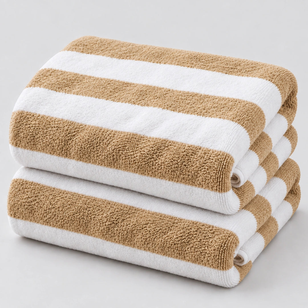Two folded striped towels stacked on a light gray background. The towels have alternating warm tan and white horizontal stripes, with a soft textured terry cloth surface.