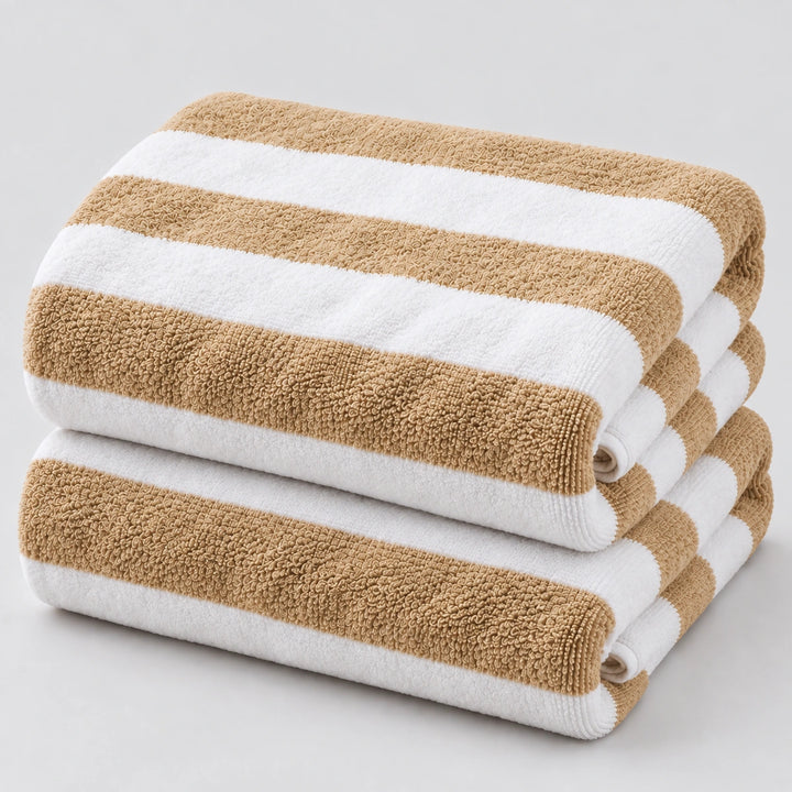 Two folded striped towels stacked on a light gray background. The towels have alternating warm tan and white horizontal stripes, with a soft textured terry cloth surface.
