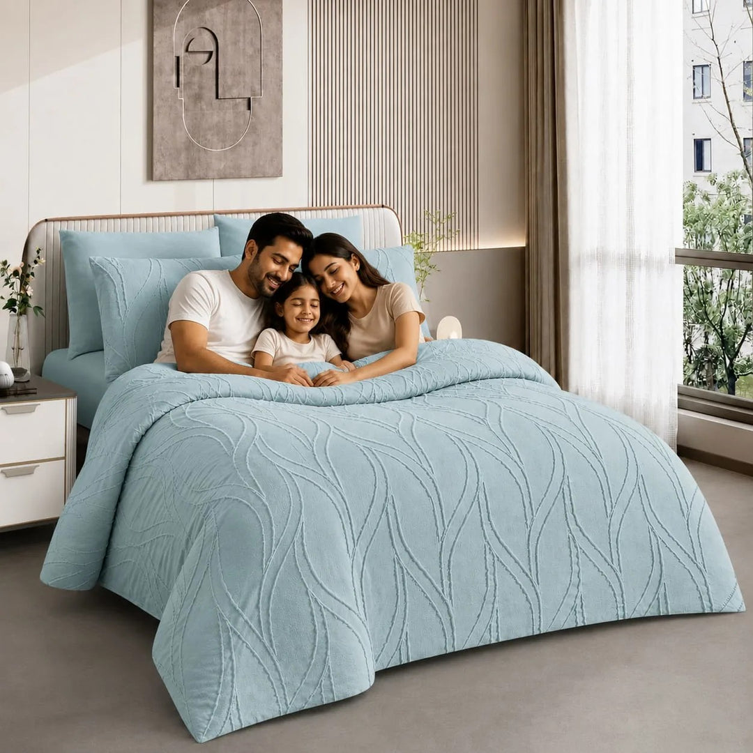A family of three lies on a bed in a modern affordable bedding sets
, covered with a light blue quilted comforter and matching pillows.