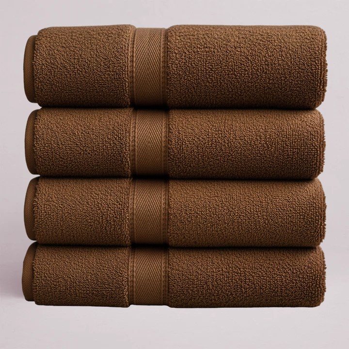 Rolled brown bath towels stacked neatly showing soft plush texture