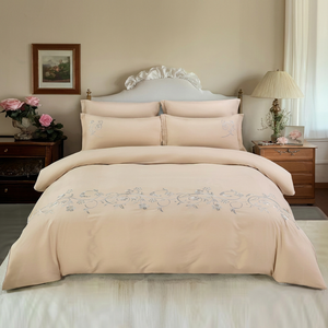Beige embroidered bedding set on a bed in a bedroom with floral decorationsin uae