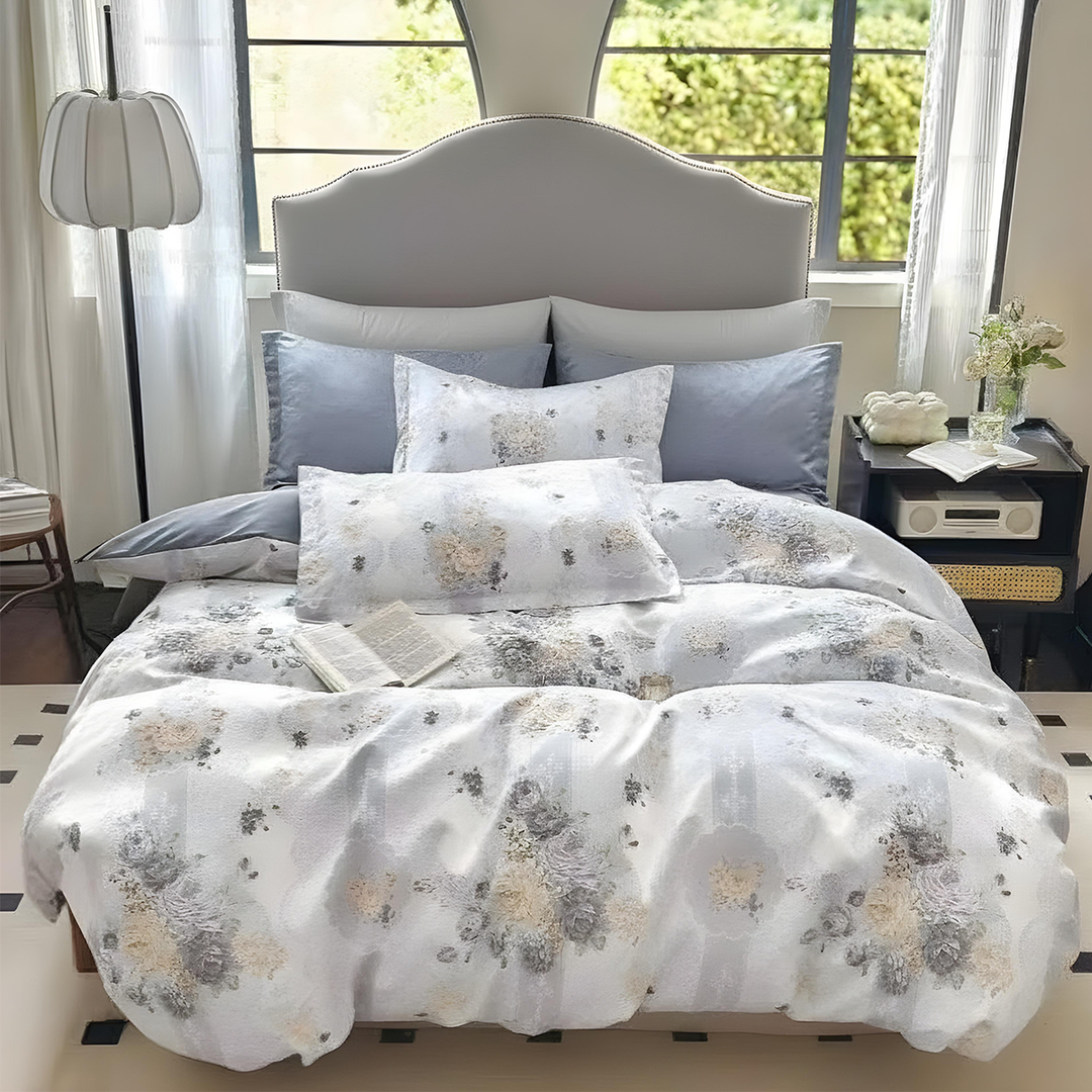Light grey bedding layered with subtle floral prints and matching pillows