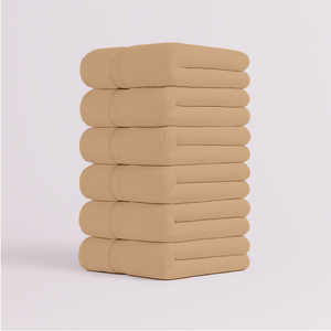 Stack of beige bath towels folded neatly with soft plush texture
