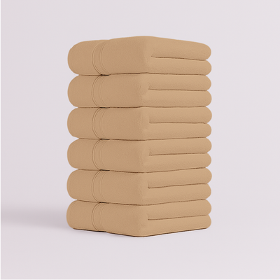 Stack of beige bath towels folded neatly with soft plush texture