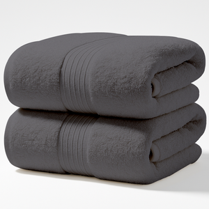 Stack of folded grey bath towels made from cotton fabric with decorative woven band