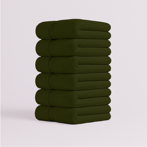 Stack of dark green bath towels folded neatly with soft plush texture