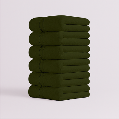 Stack of dark green bath towels folded neatly with soft plush texture