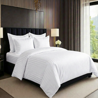 White hotel style bedding set with striped duvet cover and pillow covers on bed
